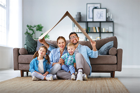 eine junge Familie sitzt in ihrer neuen Wohnung unter einem Pappdach auf dem Boden